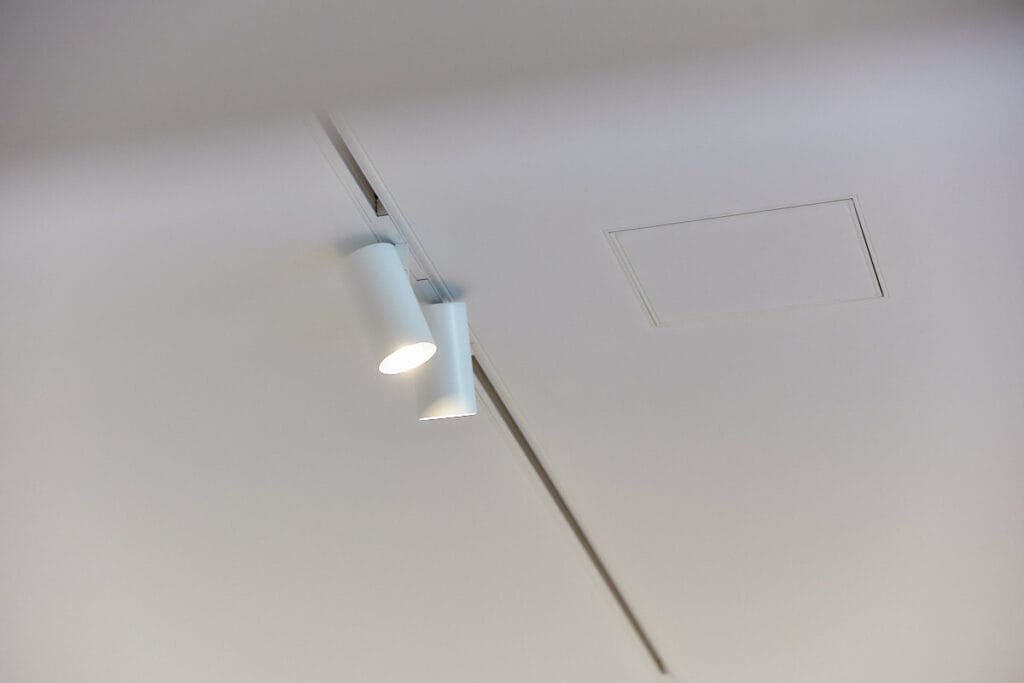 MonaTechnic inspectieluik naadloos geïntegreerd in een polyester spanplafond met railverlichting.