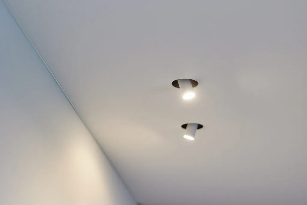 Geïntegreerde inbouwspots in een naadloos polyester spanplafond voor een strakke en minimalistische verlichting.