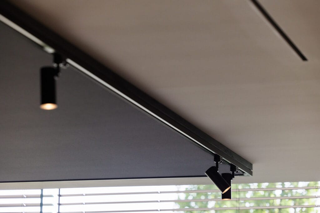 Naadloos polyester spanplafond met geïntegreerde zwarte railverlichting in een modern interieur.