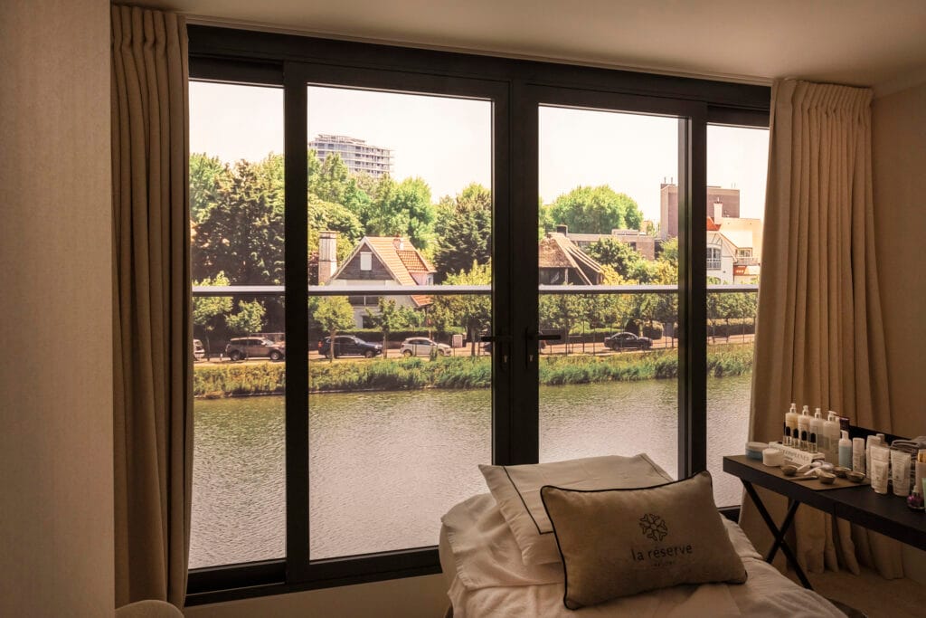 Spanplafond met geïntegreerde verlichting in een luxe wellnessruimte met uitzicht op het water.